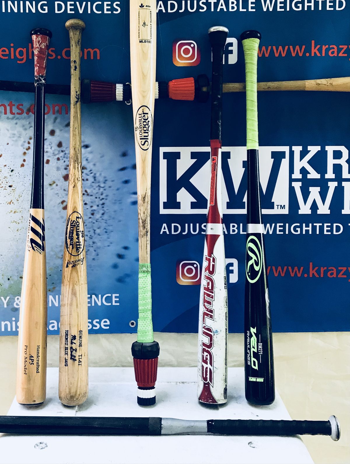 Krazy Weights prototypes clamped to the knob end of wood and aluminum baseball bats